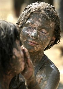 WESTLAND, MI - JULY 10: Courtney Thompson, age 12, of Romulus, Michigan decorates her friend's face while playing in a giant lake of mud during Mud Day at Nankin Park July 10, 2007 in Westland, Michigan. The annual Mud Day event consists of 200 tons of topsoil combined with 20,000 gallons of water and is sponsored by the Wayne County parks and recreation department. (Bill Pugliano/Getty Images)